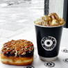 Gobelet en papier double paroi noir personnalisé avec le logo 'Black box donuts' utilisé pour servir une tasse de chocolat chaud